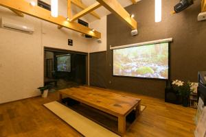 a living room with a wooden table and a large screen at Waso Mukuge in Sakaiminato