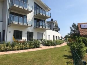 a white building with balconies and a yard at Ferienwohnung Oberdeck 2.06 in Glowe
