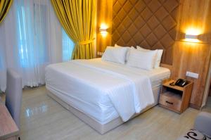a bedroom with a large white bed and yellow curtains at Lit Suites in Abuja