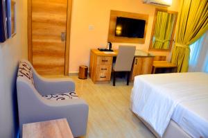 a hotel room with a bed and a desk and a table at Lit Suites in Abuja