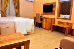 a hotel room with a bed and a desk with a television at Lit Suites in Abuja