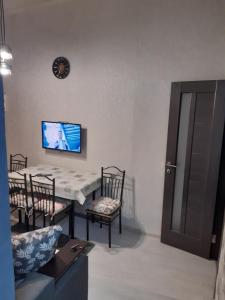 una sala da pranzo con tavolo, sedie e TV di Квартира студія подобово 1 a Lviv
