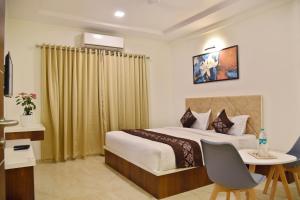 a bedroom with a bed and a desk with a chair at Hotel Grand Ecotel, Aurangabad in Aurangabad