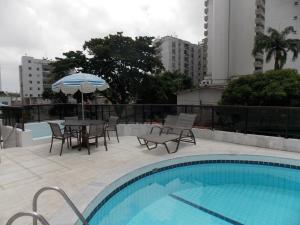 a pool with a table and chairs and an umbrella at BOA VIAGEM PROX AO MAR in Recife