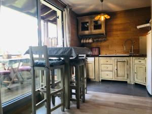 een keuken met houten kasten en een tafel en stoelen bij La Corneille Blanche in Les Deux Alpes