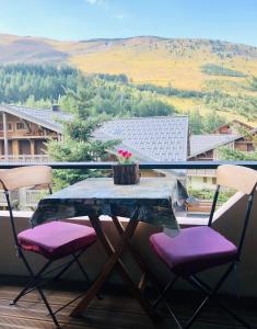 uma mesa e 2 cadeiras numa varanda com vista em La Corneille Blanche em Les Deux Alpes