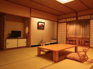 a living room with a table and a tv at Izumiya Ryokan in Kyoto