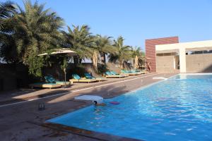 a swimming pool with lounge chairs and palm trees at 7 Seasons resort & Spa in Jamnagar