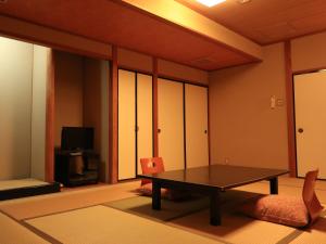 a living room with a table and a tv at Izumiya Ryokan in Kyoto