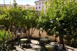 un patio con mesas, sillas y árboles en Alex Place, en Roma