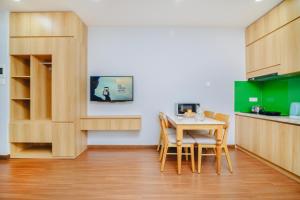 una cocina con armarios de madera, mesa y sillas en Monalisa Apartment, en Da Nang