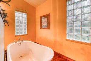 y baño con bañera, paredes de color naranja y ventanas. en Creekside Cowa-Bungalow! en Moab