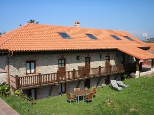 ein Haus mit orangefarbenem Dach und einem Tisch und Stühlen in der Unterkunft Posada Las Mañanitas in Cóbreces