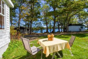 a table and chairs in a yard with a view of the water at Harpswell Bay House in East Harpswell