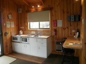 cocina con armarios blancos, fregadero y ventana en Duffy's Country Accommodation, en Westerway