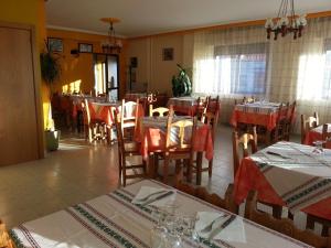 Hostal Atila في Ricobayo: مطعم به طاولات وكراسي به قماش طاولة حمراء وبيضاء