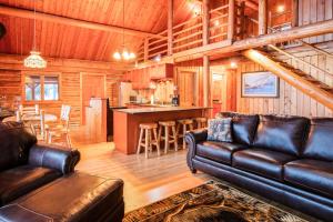 a living room with a leather couch and a kitchen at Blacktail Cabin in Somers