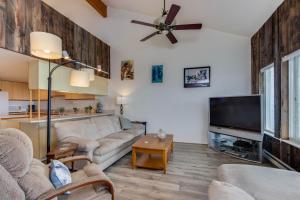 uma sala de estar com um sofá e uma televisão de ecrã plano em Whaler's Getaway em Depoe Bay