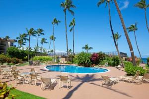 uma piscina com cadeiras e palmeiras num resort em Hale Ono Loa 208 em Honokowai