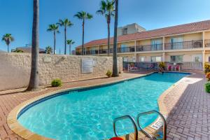 einen Pool vor einem Hotel mit Palmen in der Unterkunft Dolphin #26 in South Padre Island