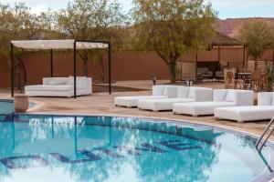 una piscina con sillas blancas y un cenador en Kasbah Tizzarouine, en Boumalne