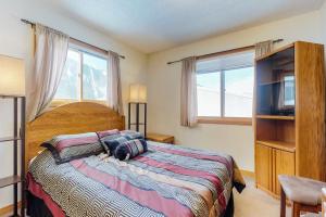 a bedroom with a bed and a tv and windows at Snowdance Condo A101 in Keystone