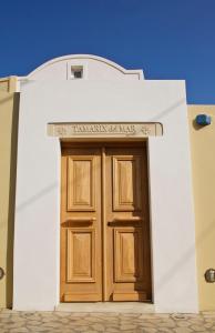 a white building with a wooden door on it at Tamarix Del Mar Suites in Kamari