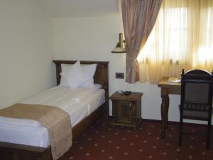 a bedroom with a bed and a desk and a chair at Hotel Castel Royal in Timişoara