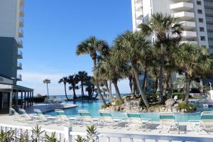 a pool with chairs and palm trees and a building at Long Beach Resort #T2-304 in Panama City Beach