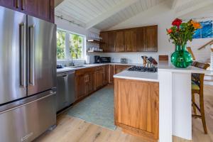 cocina con armarios de madera y nevera de acero inoxidable en Hale Kailea TVNC #4241, en Hanalei