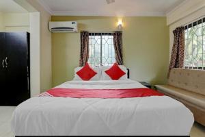 a bedroom with a large white bed with red pillows at Roundcube Guest House in Palolem