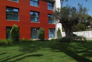 a red building with a tree in front of it at Apartamentos Royal Marina Gardens in Castelldefels