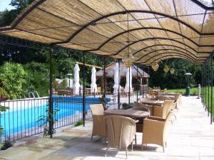 a patio with tables and chairs and a swimming pool at Ravenwood Hall Hotel in Bury Saint Edmunds