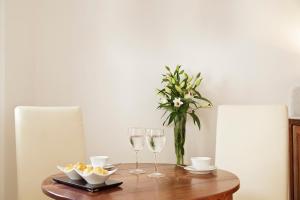 a table with wine glasses and a vase of flowers at Tamarix Del Mar Suites in Kamari