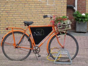 ein orangefarbenes Fahrrad mit einem Korb voller Blumen in der Unterkunft Bij Paul in Almere in Almere