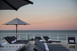 朗布蘭奇的住宿－Wave Resort，海滩上的一排躺椅和遮阳伞