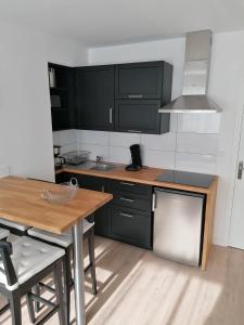 a kitchen with black cabinets and a wooden table at Le Voltaire-Sleep in Normandie in Saint Lo