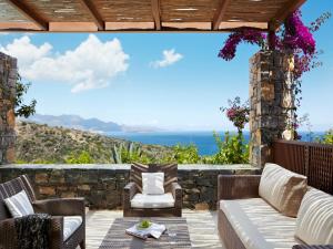 a patio with a couch and chairs and the ocean at Daios Cove in Agios Nikolaos