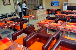 a restaurant with tables and chairs with people in the kitchen at Lit Suites in Abuja