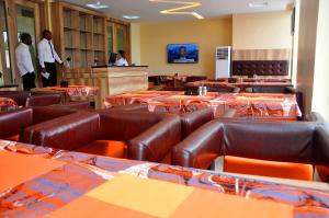 a waiting room with brown leather chairs and people in a room at Lit Suites in Abuja