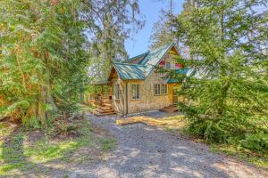 a log cabin in the woods with a gravel driveway at Camano Writer's Cottage in Indian Beach