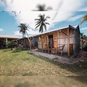 een klein houten huis met een veranda en 2 palmbomen bij Gravier beach house in Rodrigues Island