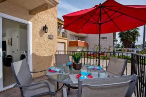 a patio with a table with a red umbrella at Villa Del Mar in San Clemente