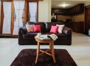 a living room with a brown leather couch and a table at Nginap at Joy House in Sleman