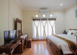 um quarto com uma cama e uma televisão de ecrã plano em Nginap at Joy House em Sleman