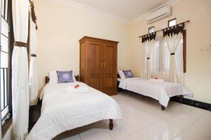 um quarto com 2 camas e lençóis brancos em Nginap at Joy House em Sleman