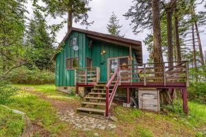 a green cabin in the woods with a large deck at Lohman Lookout in Eastsound