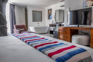 a bedroom with a bed with a television and a tub at MayaFair Design Hotel in Cancún