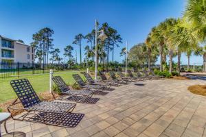 a row of lounge chairs in a park with palm trees at Reflections At Bay Point II in Panama City Beach