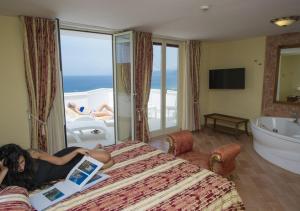 a woman laying on a bed in a hotel room with a laptop at Hotel Baia in Palinuro